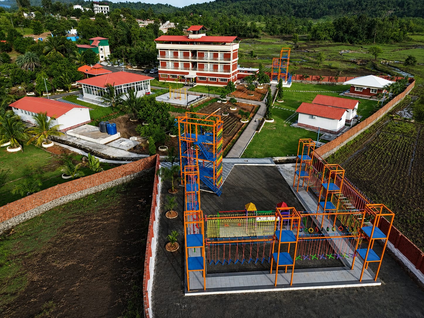 The adventure park from above: the climbing frames and rope course laid out below the main building and the hills
