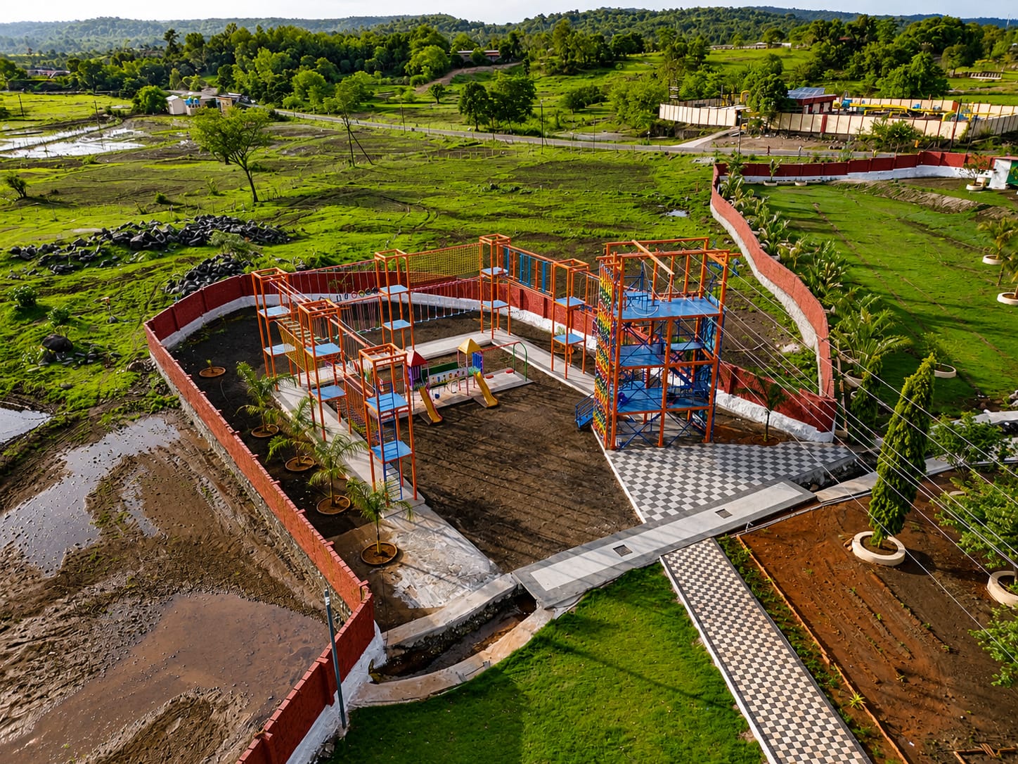 The adventure park from above: rope course, climbing tower and play area set in the green valley