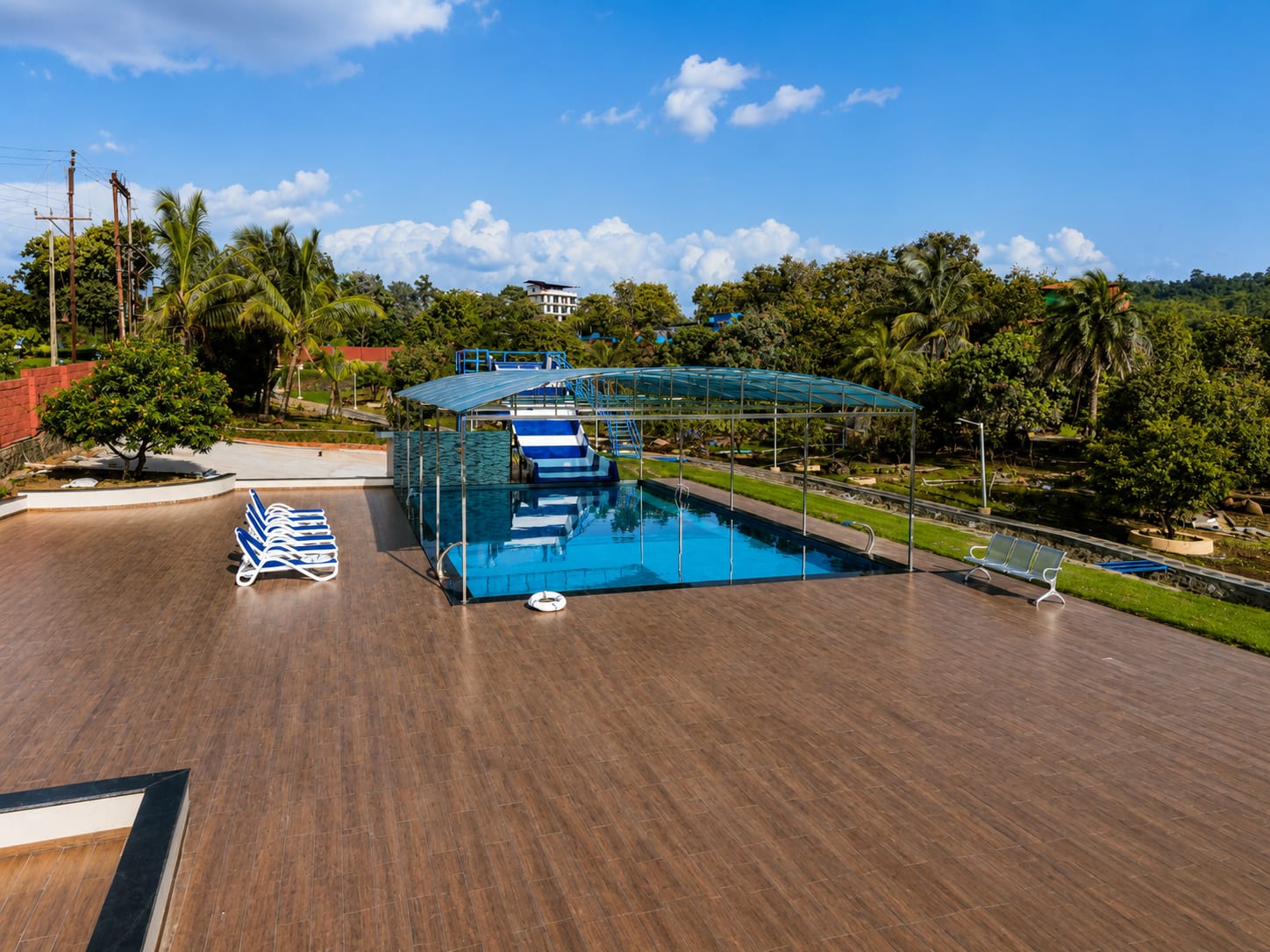 Open-air pool with water slide, loungers and the hills beyond