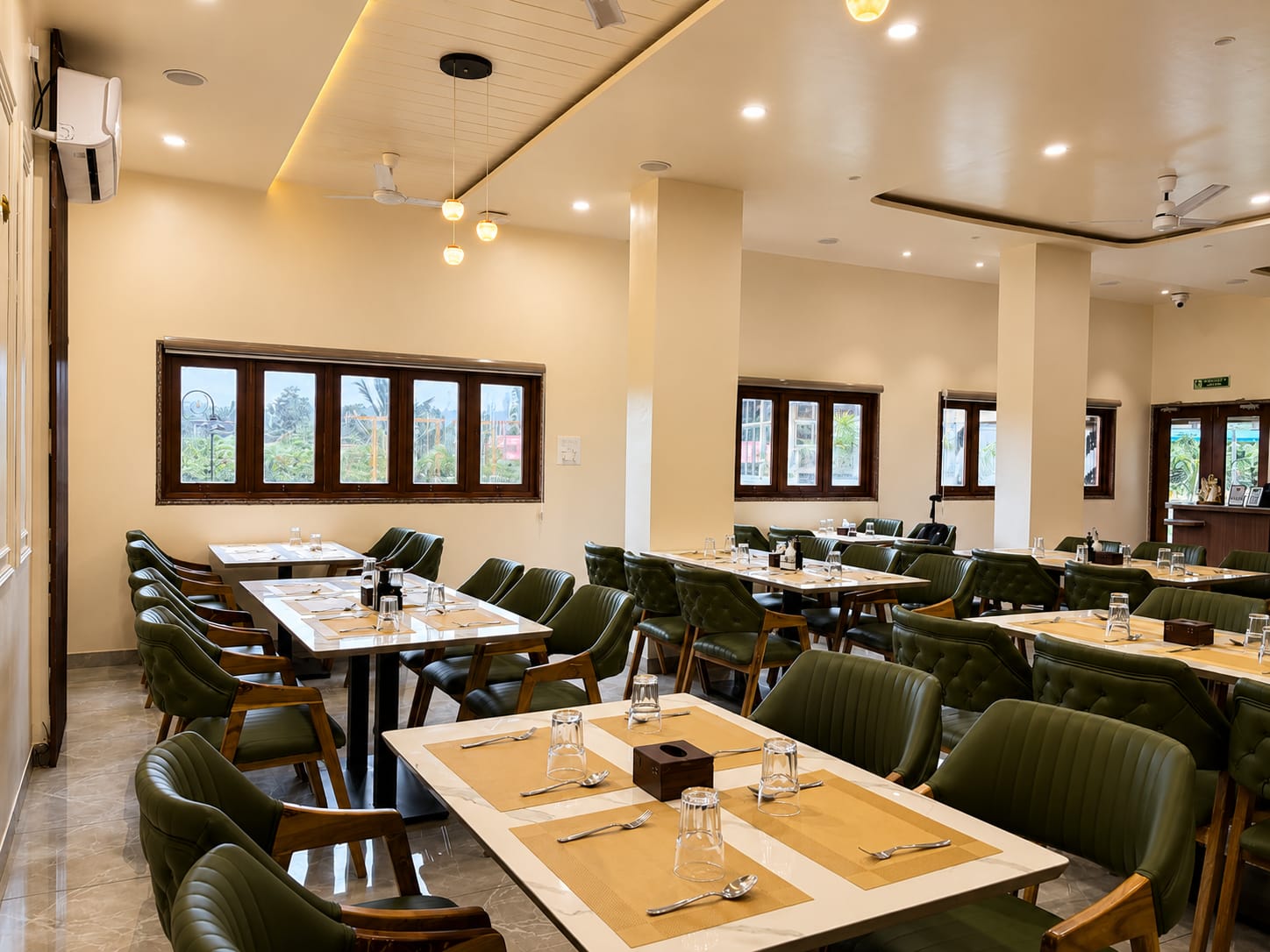 The restaurant dining room with green leather chairs and laid tables